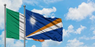 İrlanda ve Marshall Adaları bayrağı birlikte beyaz bulutlu mavi gökyüzüne karşı rüzgarda sallayarak. Diplomasi kavramı, uluslararası ilişkiler.