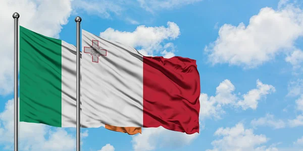 Bandera de Irlanda y Malta ondeando en el viento contra el cielo azul nublado blanco juntos. Concepto diplomático, relaciones internacionales . — Foto de Stock