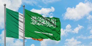 İrlanda ve Suudi Arabistan bayrağı birlikte beyaz bulutlu mavi gökyüzüne karşı rüzgarsal sallayarak. Diplomasi kavramı, uluslararası ilişkiler.