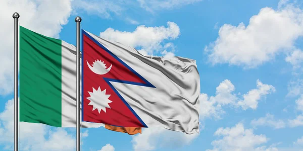 Bandera de Irlanda y Nepal ondeando en el viento contra el cielo azul nublado blanco juntos. Concepto diplomático, relaciones internacionales . — Foto de Stock