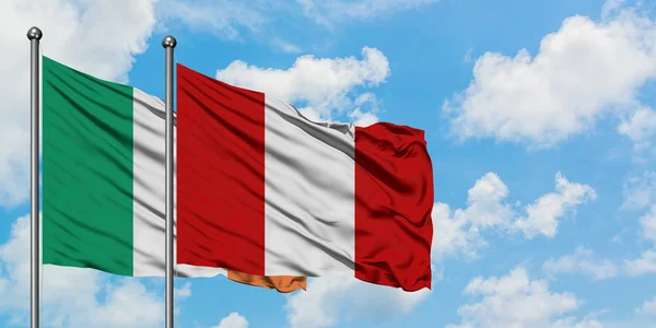 Bandera de Irlanda y Perú ondeando en el viento contra el cielo azul nublado blanco juntos. Concepto diplomático, relaciones internacionales . — Foto de Stock