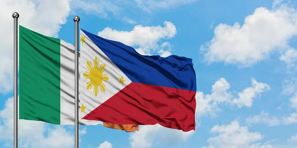 Bandera de Irlanda y Filipinas ondeando en el viento contra el cielo azul nublado blanco juntos. Concepto diplomático, relaciones internacionales . — Foto de Stock