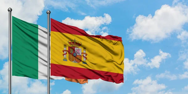 Irlanda e Spagna sventolano bandiera nel vento contro bianco cielo blu nuvoloso insieme. Concetto di diplomazia, relazioni internazionali . — Foto Stock