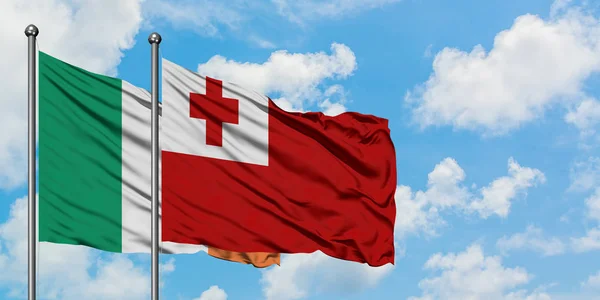 Bandera de Irlanda y Tonga ondeando en el viento contra el cielo azul nublado blanco juntos. Concepto diplomático, relaciones internacionales . — Foto de Stock