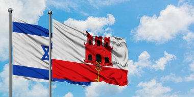 İsrail ve Cebelitarık bayrağı birlikte beyaz bulutlu mavi gökyüzüne karşı rüzgarda sallayarak. Diplomasi kavramı, uluslararası ilişkiler.