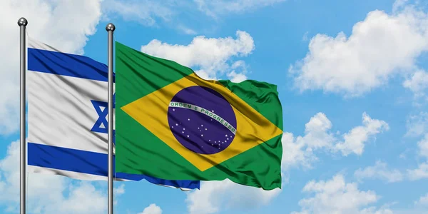 Israel e a bandeira do Brasil agitando no vento contra o céu azul nublado branco juntos. Conceito de diplomacia, relações internacionais . — Fotografia de Stock