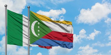 İtalya ve Komorbayrağı birlikte beyaz bulutlu mavi gökyüzüne karşı rüzgarda sallayarak. Diplomasi kavramı, uluslararası ilişkiler.