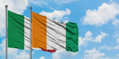 İtalya ve Fildişi Sahili bayrağı birlikte beyaz bulutlu mavi gökyüzüne karşı rüzgarda sallayarak. Diplomasi kavramı, uluslararası ilişkiler.