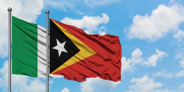 İtalya ve Doğu Timor bayrağı birlikte beyaz bulutlu mavi gökyüzüne karşı rüzgarsal sallayarak. Diplomasi kavramı, uluslararası ilişkiler.