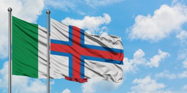 İtalya ve Faroe Adaları bayrağı birlikte beyaz bulutlu mavi gökyüzüne karşı rüzgarda sallayarak. Diplomasi kavramı, uluslararası ilişkiler.