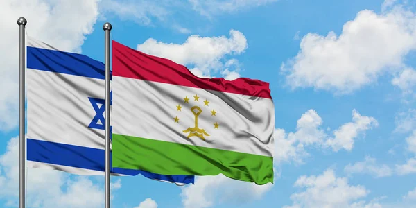 Bandera de Israel y Tayikistán ondeando en el viento contra el cielo azul nublado blanco juntos. Concepto diplomático, relaciones internacionales . — Foto de Stock