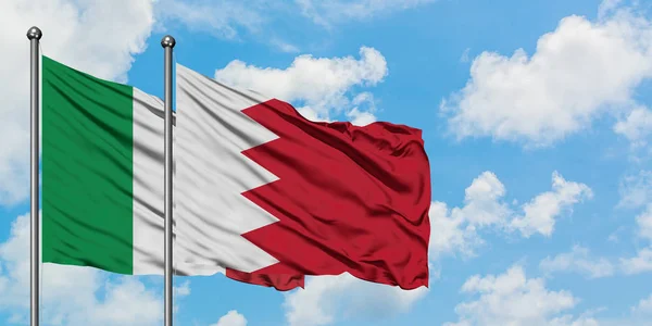 Bandera de Italia y Bahréin ondeando en el viento contra el cielo azul nublado blanco juntos. Concepto diplomático, relaciones internacionales . — Foto de Stock