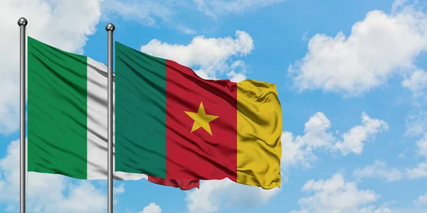 Bandera de Italia y Camerún ondeando en el viento contra el cielo azul nublado blanco juntos. Concepto diplomático, relaciones internacionales . — Foto de Stock