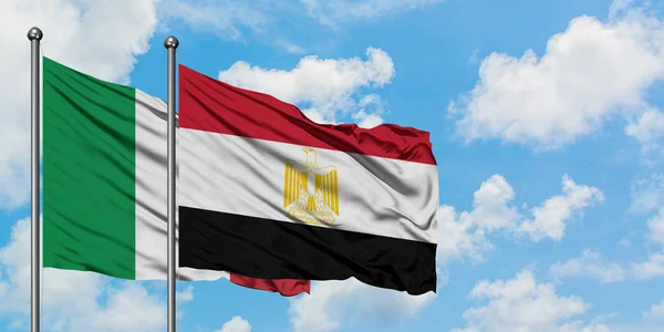 Bandera de Italia y Egipto ondeando en el viento contra el cielo azul nublado blanco juntos. Concepto diplomático, relaciones internacionales . — Foto de Stock