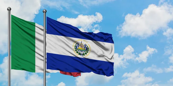 Bandera de Italia y El Salvador ondeando en el viento contra el cielo azul nublado blanco juntos. Concepto diplomático, relaciones internacionales . — Foto de Stock