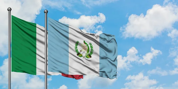 Η σημαία της Ιταλίας και της Γουατεμάλας κουνώντας τον άνεμο ενάντια στον λευκό θολό γαλάζιο ουρανό μαζί. Φιλοσοφία της διπλωματίας, διεθνείς σχέσεις. — Φωτογραφία Αρχείου