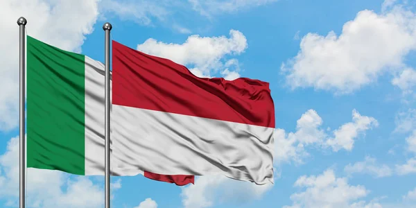 Bandera de Italia e Indonesia ondeando en el viento contra el cielo azul nublado blanco juntos. Concepto diplomático, relaciones internacionales . — Foto de Stock