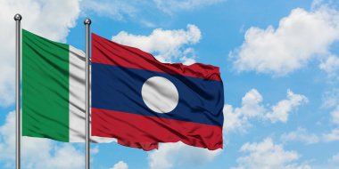 İtalya ve Laos bayrağı birlikte beyaz bulutlu mavi gökyüzüne karşı rüzgarda sallayarak. Diplomasi kavramı, uluslararası ilişkiler.