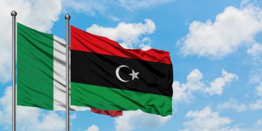 İtalya ve Libya bayrağı birlikte beyaz bulutlu mavi gökyüzüne karşı rüzgarsal sallayarak. Diplomasi kavramı, uluslararası ilişkiler.