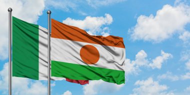 İtalya ve Nijer bayrağı rüzgarda dalgalanırken beyaz bulutlu gökyüzüne karşı birlikte. Diplomasi kavramı, uluslararası ilişkiler.