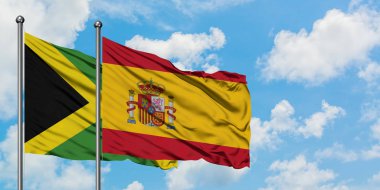 Jamaika ve İspanya bayrağı birlikte beyaz bulutlu mavi gökyüzüne karşı rüzgarda sallayarak. Diplomasi kavramı, uluslararası ilişkiler.