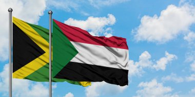 Jamaika ve Sudan bayrağı birlikte beyaz bulutlu mavi gökyüzüne karşı rüzgarda sallayarak. Diplomasi kavramı, uluslararası ilişkiler.