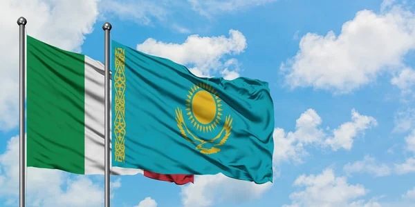 Bandera de Italia y Kazajstán ondeando en el viento contra el cielo azul nublado blanco juntos. Concepto diplomático, relaciones internacionales . — Foto de Stock