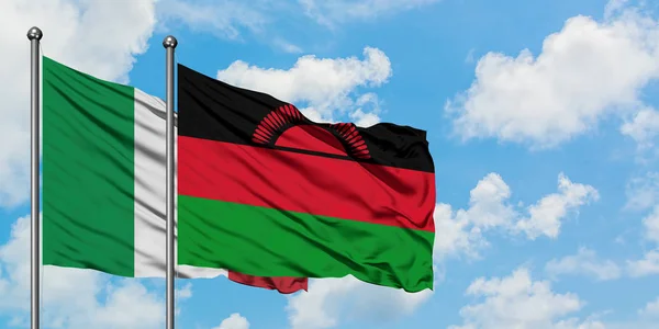 Bandera de Italia y Malawi ondeando en el viento contra el cielo azul nublado blanco juntos. Concepto diplomático, relaciones internacionales . — Foto de Stock