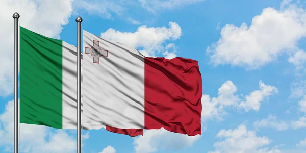 Bandera de Italia y Malta ondeando en el viento contra el cielo azul nublado blanco juntos. Concepto diplomático, relaciones internacionales . — Foto de Stock