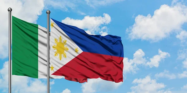 Bandera de Italia y Filipinas ondeando en el viento contra el cielo azul nublado blanco juntos. Concepto diplomático, relaciones internacionales . — Foto de Stock