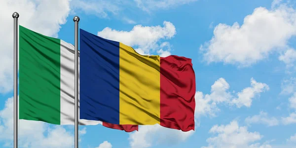 Bandera de Italia y Rumanía ondeando en el viento contra el cielo azul nublado blanco juntos. Concepto diplomático, relaciones internacionales . — Foto de Stock