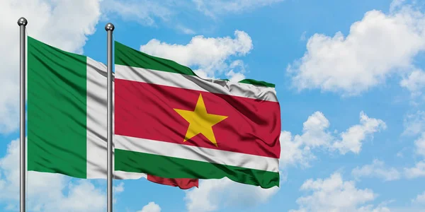 Bandera de Italia y Surinam ondeando en el viento contra el cielo azul nublado blanco juntos. Concepto diplomático, relaciones internacionales . — Foto de Stock