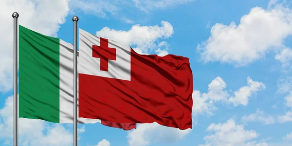 Bandera de Italia y Tonga ondeando en el viento contra el cielo azul nublado blanco juntos. Concepto diplomático, relaciones internacionales . — Foto de Stock