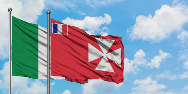 Italia y Wallis Y la bandera de Futuna ondeando en el viento contra el cielo azul nublado blanco juntos. Concepto diplomático, relaciones internacionales . — Foto de Stock
