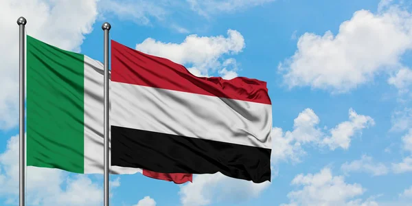 Bandera de Italia y Yemen ondeando en el viento contra el cielo azul nublado blanco juntos. Concepto diplomático, relaciones internacionales . — Foto de Stock