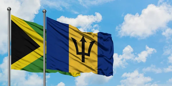 Jamaica és Barbados zászló integetett a szél ellen, fehér felhős kék ég együtt. Diplomáciai koncepció, nemzetközi kapcsolatok. — Stock Fotó