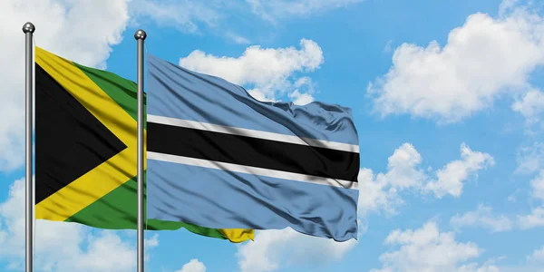 Jamaica és Botswana zászló integetett a szél ellen, fehér felhős kék ég együtt. Diplomáciai koncepció, nemzetközi kapcsolatok. — Stock Fotó