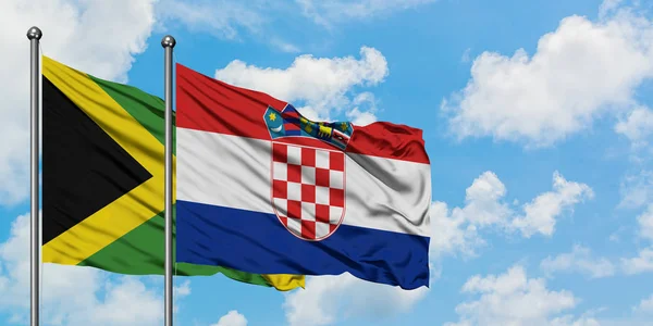 Bandera de Jamaica y Croacia ondeando en el viento contra el cielo azul nublado blanco juntos. Concepto diplomático, relaciones internacionales . — Foto de Stock