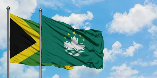 Jamaica and Macao flag waving in the wind against white cloudy blue sky together. Diplomacy concept, international relations.