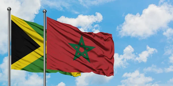 Bandera de Jamaica y Marruecos ondeando en el viento contra el cielo azul nublado blanco juntos. Concepto diplomático, relaciones internacionales . — Foto de Stock