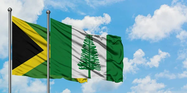 Bandera de Jamaica y Norfolk Island ondeando en el viento contra el cielo azul nublado blanco juntos. Concepto diplomático, relaciones internacionales . — Foto de Stock