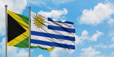 Jamaika ve Uruguay bayrağı birlikte beyaz bulutlu mavi gökyüzüne karşı rüzgarda sallayarak. Diplomasi kavramı, uluslararası ilişkiler.
