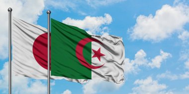 Japonya ve Cezayir bayrağı birlikte beyaz bulutlu mavi gökyüzüne karşı rüzgarda sallayarak. Diplomasi kavramı, uluslararası ilişkiler.