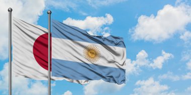 Japonya ve Arjantin bayrağı birlikte beyaz bulutlu mavi gökyüzüne karşı rüzgarda sallayarak. Diplomasi kavramı, uluslararası ilişkiler.