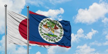 Japonya ve Belize bayrağı birlikte beyaz bulutlu mavi gökyüzüne karşı rüzgarda sallayarak. Diplomasi kavramı, uluslararası ilişkiler.