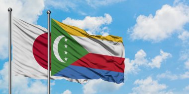 Japonya ve Komorbayrağı birlikte beyaz bulutlu mavi gökyüzüne karşı rüzgarda sallayarak. Diplomasi kavramı, uluslararası ilişkiler.