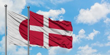 Japonya ve Danimarka bayrağı birlikte beyaz bulutlu mavi gökyüzüne karşı rüzgarda sallayarak. Diplomasi kavramı, uluslararası ilişkiler.