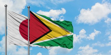 Japonya ve Guyana bayrağı birlikte beyaz bulutlu mavi gökyüzüne karşı rüzgarda sallayarak. Diplomasi kavramı, uluslararası ilişkiler.