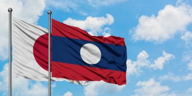 Japonya ve Laos bayrağı birlikte beyaz bulutlu mavi gökyüzüne karşı rüzgarda sallayarak. Diplomasi kavramı, uluslararası ilişkiler.