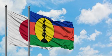 Japonya ve Yeni Kaledonya bayrağı birlikte beyaz bulutlu mavi gökyüzüne karşı rüzgarda sallayarak. Diplomasi kavramı, uluslararası ilişkiler.